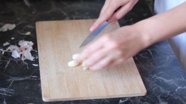 Ev hanımı, tahtadan sarımsak kesiyor.