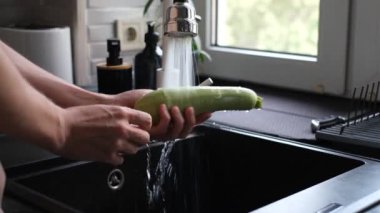 Bir adam kabağı yakın planda yıkıyor.