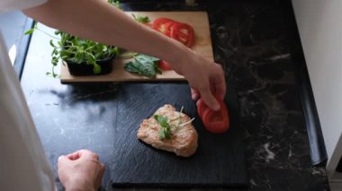 Genç Avrupalı bir adam sebze ve otlarla dolu bir tabakta biftek servis ediyor.