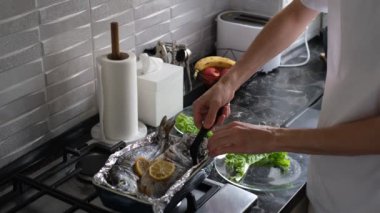 Bir adam fırında Dorado balığı servis ediyor.