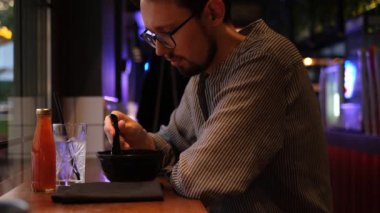 Japon restoranında sakallı ve ramen yiyen genç bir adamın portresi.
