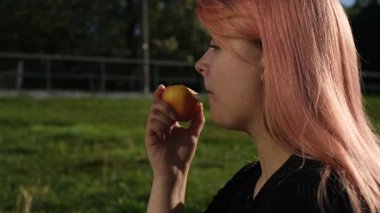 Güneşli yaz gününde elma yiyen şişman gencin portresi.