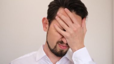 Genç bir adamın portresi. Gözlüklerini çıkarıyor ve gözlerini yorgunluktan ovalıyor.