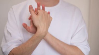 Genç adam parmaklarını birbirine yaklaştırıyor.