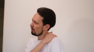 Genç adam omuzlarına ve boynuna masaj yapıyor.