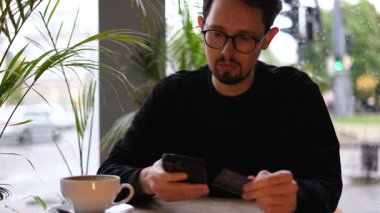 Genç bir adam kredi kartıyla telefonuyla online alışveriş yapıyor.