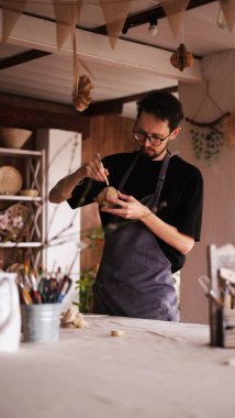 Genç seramikçi stüdyoda kil çömlek yapıyor.