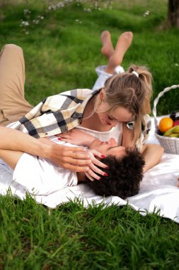 Genç çift bahar pikniğinde çiçek açan parkta sarılıyor.