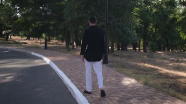 Erkek menajer teneffüste parkta yürüyor güneşli bir bahar gününde arkadan.