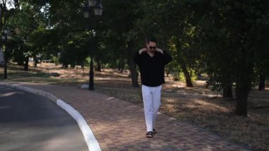 Erkek menajer güneşli bahar gününde parkta geziyor.