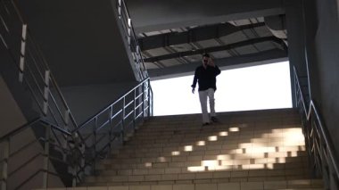 Genç erkek müdür işten sonra bir iş merkezinin merdivenlerinden aşağı iniyor.