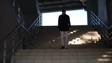 Genç bir erkek yönetici bir iş merkezinin merdivenlerine tırmanarak işe gider.