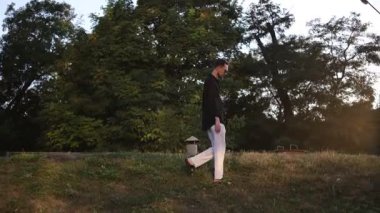 Genç adam gün batımında parkta yürümekten zevk alıyor.