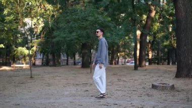 Genç yakışıklı bir adam yaz günü gün doğumunda parkta yürüyor.