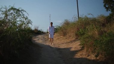 Genç yakışıklı adam gün doğumunda yamaçlarda koşuyor.