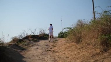 Genç yakışıklı adam gün doğumunda yamaçlarda koşuyor.