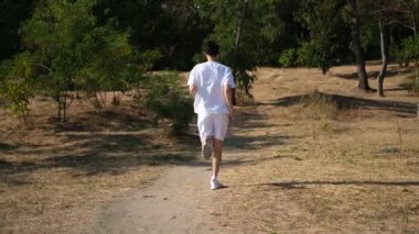 Genç sporcu bir yaz günü deniz kenarındaki yamaçlarda koşar.