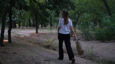 Genç bir kadın yaz günü şafak vakti parkta yürüyor.