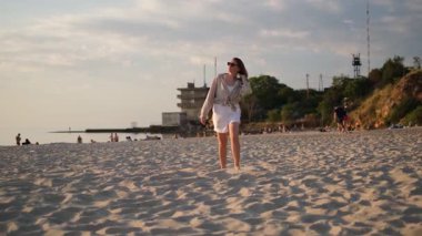 Genç bir kadın yaz günü şafak vakti kumsalda koşar.