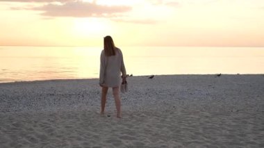 Genç bir kadın yaz günü şafak vakti kumsalda koşar.