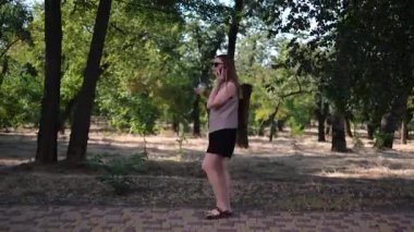 Genç bir kadın elinde bir fincan kahveyle işe giderken telefonda konuşuyor.