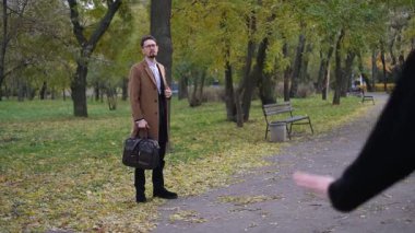 İki arkadaş, bir kadın ve bir adam rüzgarlı bir sonbahar gününde parkta yürümek için buluştular.