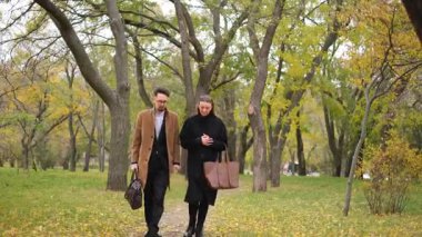 İki arkadaş, bir kadın ve bir adam rüzgarlı bir sonbahar gününde parkta yürümek için buluştular.