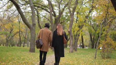 İki arkadaş, bir kadın ve bir adam rüzgarlı bir sonbahar gününde parkta yürümek için buluştular.