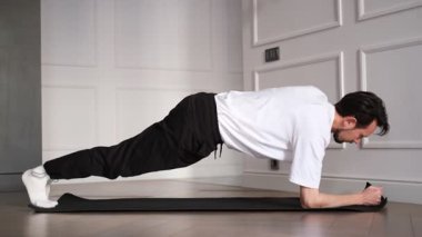 Genç adam sabahları evde tahta egzersizleri yapıyor.