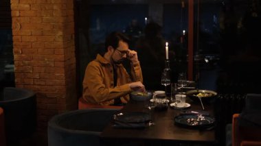 Genç Avrupalı adam restoranda akşam yemeğinde sebze Yunan salatası yiyor.