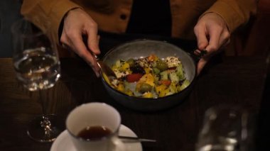 Genç Avrupalı adam restoranda akşam yemeğinde sebze Yunan salatası yiyor.