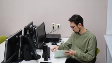 Bilgisayar masasında günlüğe yazan genç erkek öğretmen.