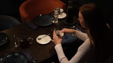 Restoranda çay içen genç bir kadın.