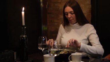 Uzun sarı saçlı genç bir kadın restoranda sebze salatası yiyor.