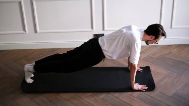 Evde sabah antrenmanı yaparken elinde kalas tutan genç bir adam.