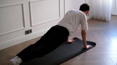 Evde sabah antrenmanı yaparken elinde kalas tutan genç bir adam.