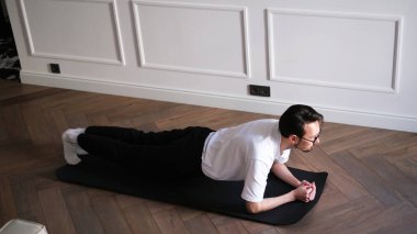 Evde sabah antrenmanı yaparken elinde kalas tutan genç bir adam.