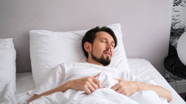 Genç esmer bir adamın portresi. Sabahın erken saatlerinde yumuşak, rahat bir yatakta mışıl mışıl uyuyor.