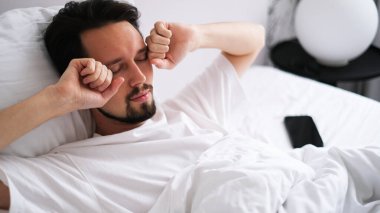 Genç esmer adam sabah uyandıktan sonra esniyor ve esniyor.