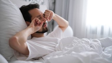 Genç esmer adam sabah uyandıktan sonra esniyor ve esniyor.