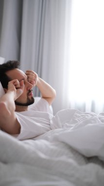 Genç esmer adam sabah uyandıktan sonra esniyor ve esniyor.