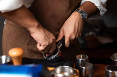 Kahve tellerini filtreye sıkıştırmak için kurcalayıcı kullanan bir baristanın yakın çekimi. Bu adım espresso yapımında çok önemli, hatta çıkarma işleminde bile..