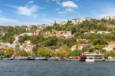 İstanbul Boğazı 'nın Avrupa yakasındaki yeşil dağların denizinden bir yaz günü rıhtımlı tekneler, geleneksel evler ve sık ağaçlarla manzarayı seyret.