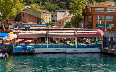 İstanbul, Türkiye - 29 Ağustos 2022: İstanbul Boğazı 'nın Asya tarafında Anadolu Kavagi Mahallesi' nin ziyaretçilerini karşılamak için yüzen restoran personelinin feribotundan bayraklar sallayarak ve dans ederek vuruldu