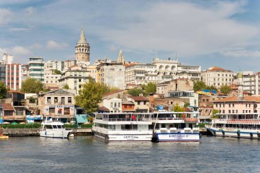 İstanbul 'un Haliç Denizi manzarası, limanlı tekneler ve uzak uçtaki Galata Kulesi, güneşli bir yaz gününde
