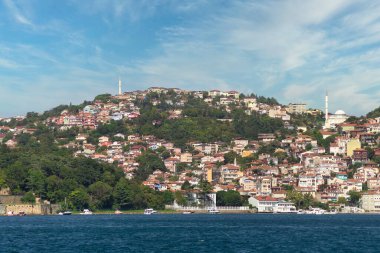 İstanbul ve Türkiye 'de yaz günlerinde geleneksel evler ve sık ağaçlarla, Asya yakasının yeşil dağlarının İstanbul Boğazı' ndan görüntüsü