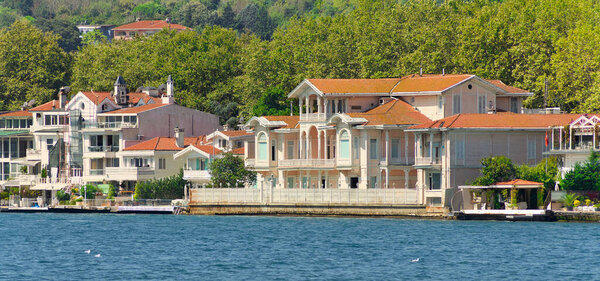 Вид на море с европейской стороны пролива Босфор, Стамбул, Турция, с традиционными домами и зелеными горами с густыми зелеными деревьями, в летний день