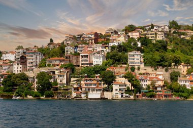 View from the sea of the green mountains of the Europian side of Bosphorus strait, with traditional houses and dense trees in a summer day before sunset, Istanbul, Turkey