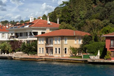 İstanbul ve Türkiye 'de yaz günlerinde geleneksel evler ve sık ağaçlarla, Asya yakasının yeşil dağlarının İstanbul Boğazı' ndan görüntüsü
