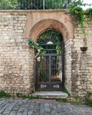 Paslanmış demir kemerli kapılı, paslı, terk edilmiş kirli girişin dış görüntüsü, Balat ilçesi, İstanbul, Türkiye 'de bir kaldırım taşı dar sokakta.